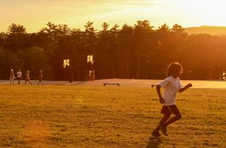 camper running on field with sun setting