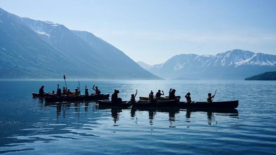 Campers in canoes on lake with mountains in background