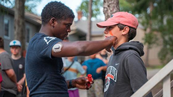 camp staff putting face paint on camper