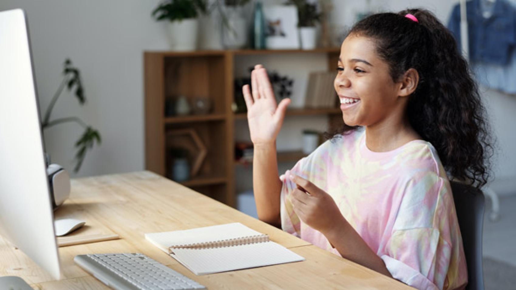 girl waving at computer screen