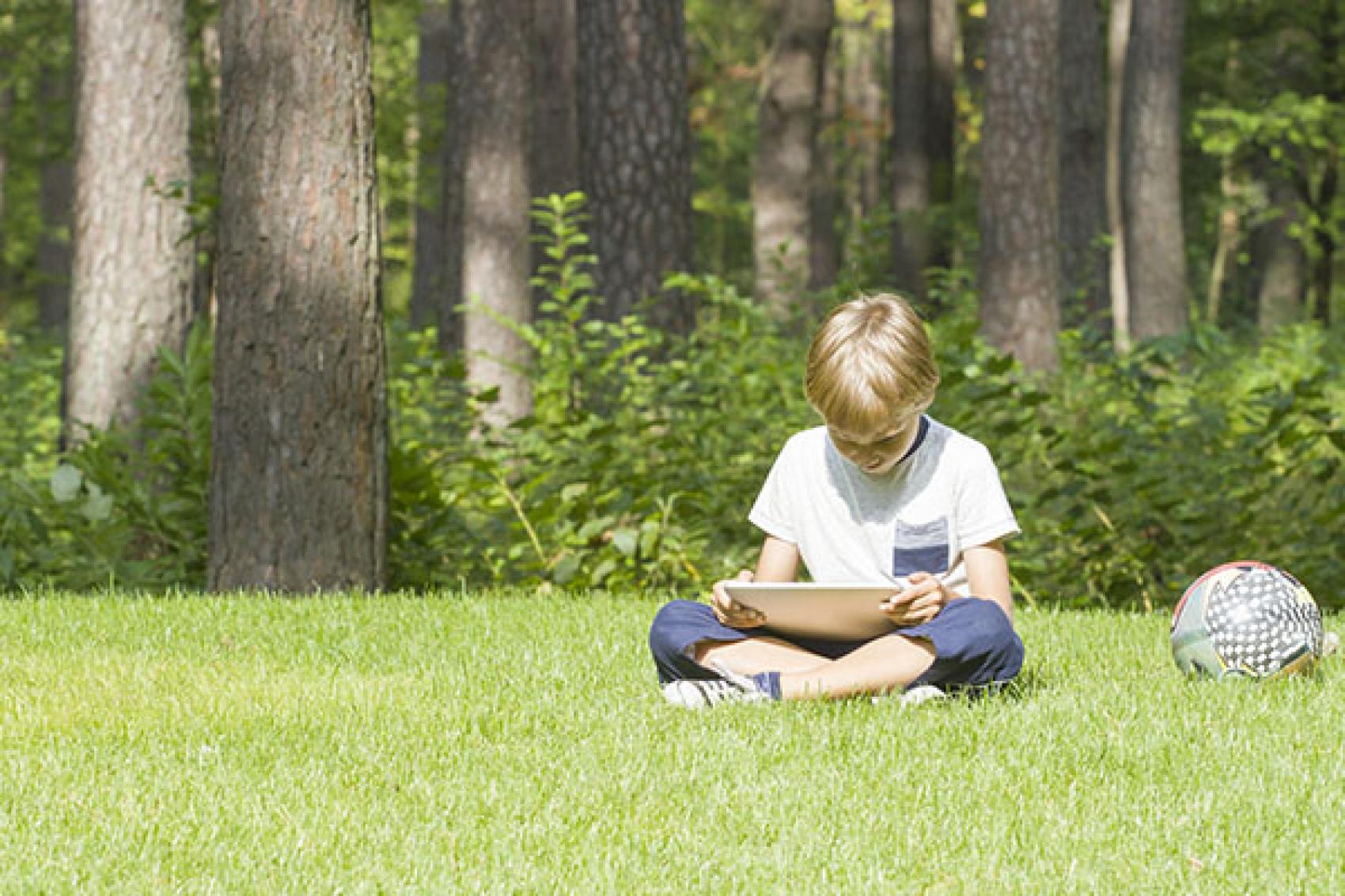 Young boy sitting outside with a tablet