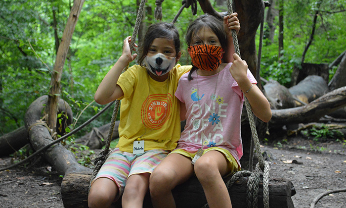 campers wearing masks sitting on log