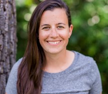 Photo of Sarah Kurtz McKinnon smiling in front of a green tree