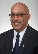 Professional photo of Michael A Swain in a black suite with thick framedglasses