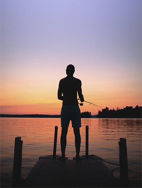 Staffer fishing on dock at sunset