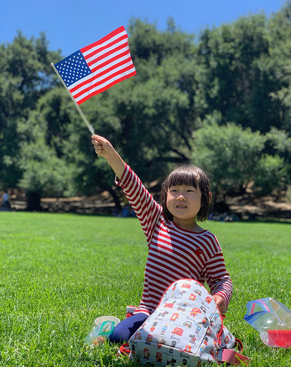 Camper sitting in grass waiving American flag