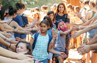 Line of campers high fiving through tunnel of staff