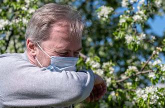 stock photo of man in mask sneezing outdoors