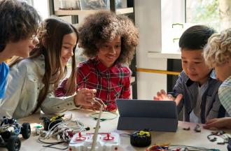 Young student working on remote-controlled car and tablet