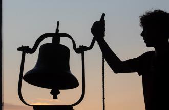 camp person ringing bell at dawn