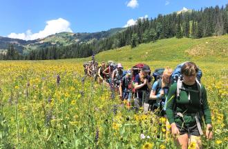 Backpackers hiking through wildflowers