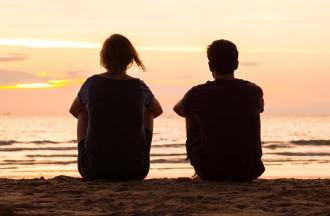 Friends sitting on beach at sunset