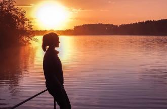 Young teenager overlooking lake at sunset