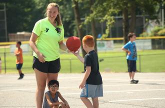 camper handing basketball to camp staff