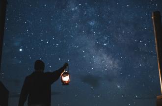 Person holding lantern with starry night sky