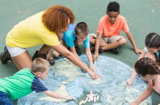 adult helping kids draw with sidewalk chalk