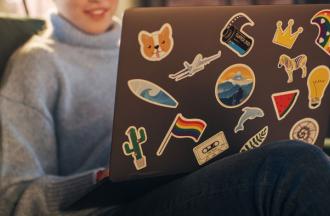 person using laptop covered in stickers