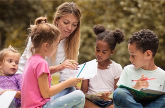 Adult helping children write
