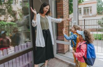 teacher welcoming children to building