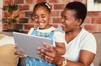 photo of woman and child looking at tablet