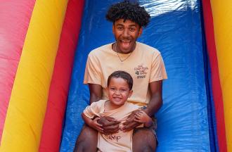 camp staff with camper on inflatable slide