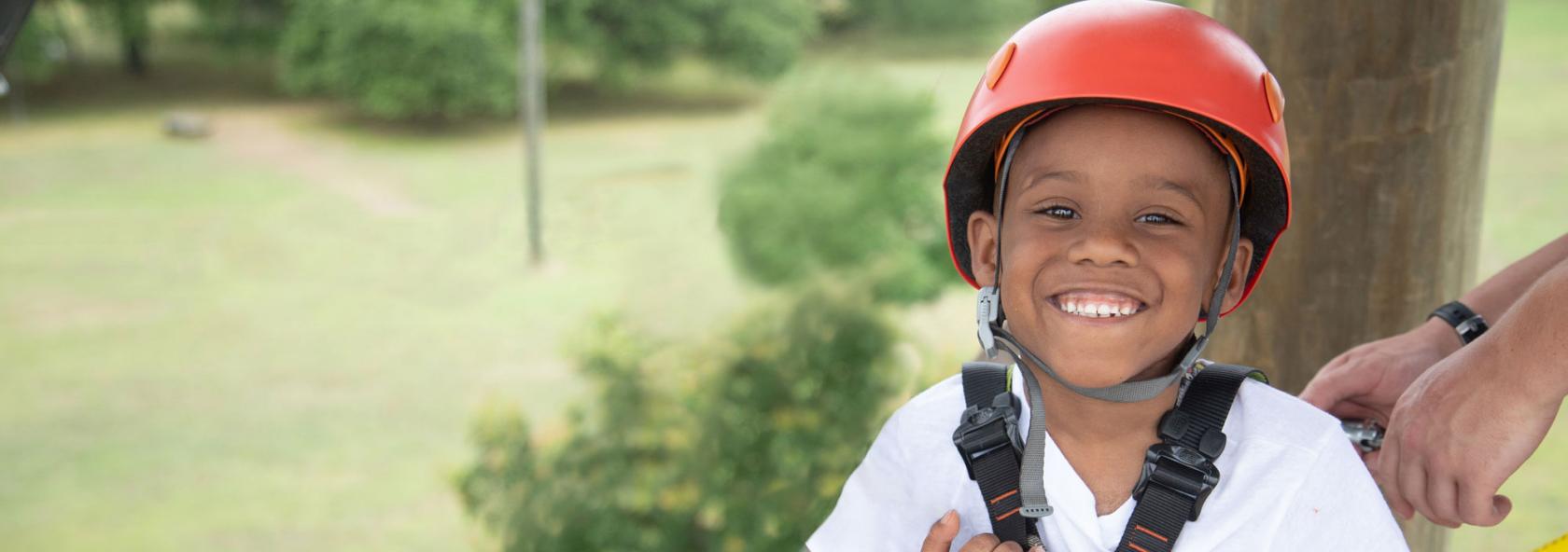 Smiling camper in gear getting ready to do a rope course