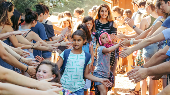 Line of campers high fiving through tunnel of staff