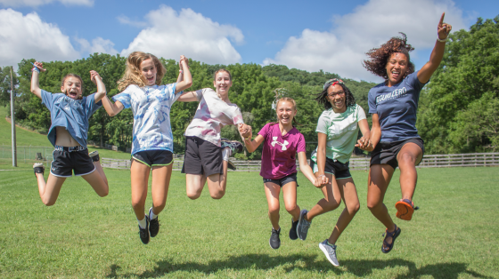 Counselor and campers jumping into the air