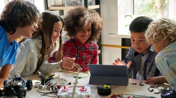 Young student working on remote-controlled car and tablet