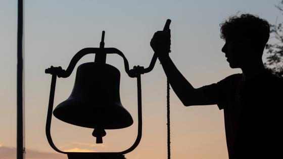 camp person ringing bell at dawn