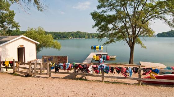 stock photo of lifejackets hanging on fence by lake