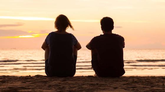 Friends sitting on beach at sunset