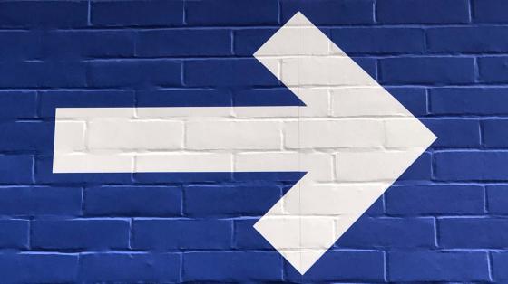 white arrow painted on blue wall