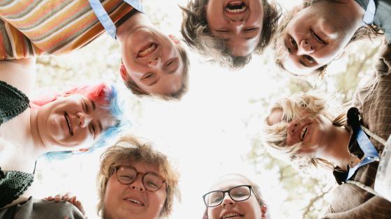 Circle of staff looking down and smiling at camera