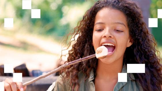 Young child eating marshmallow off stick