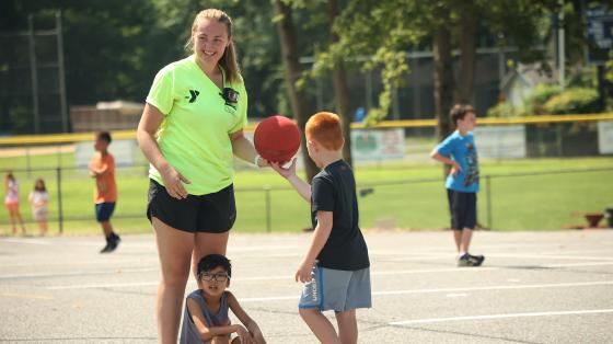 camper handing basketball to camp staff