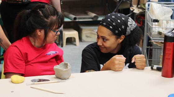 camper and staff doing pottery