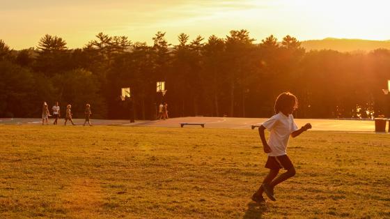 camper running on field with sun setting