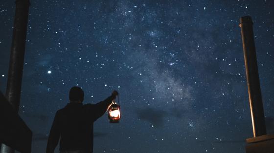 Person holding lantern with starry night sky