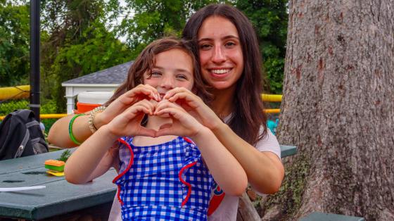 camper and staff making heart hands