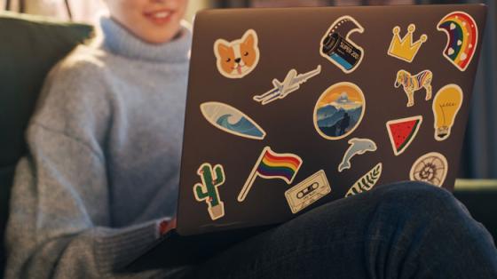 person using laptop covered in stickers