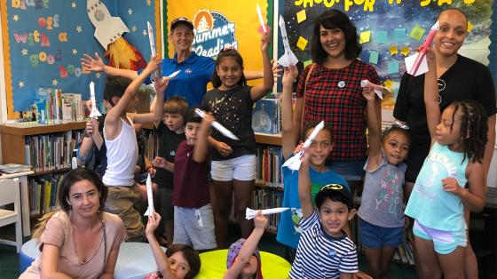 kids with teachers holding paper rockets