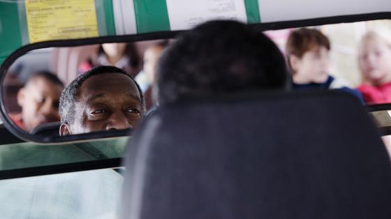 Bus driver looking at kids in rear-view mirror