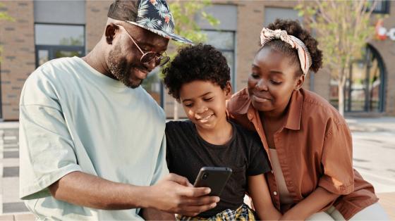 parents and child looking at phone