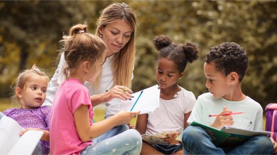 Adult helping children write