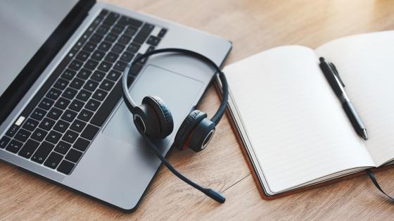 Laptop with a headset, pen, and notebook