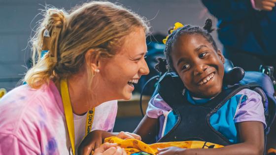 camper using wheelchair smiling with camp staff