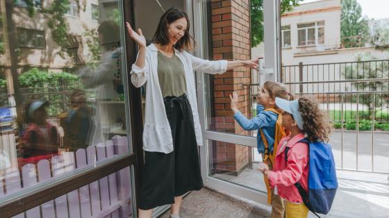 teacher welcoming children to building