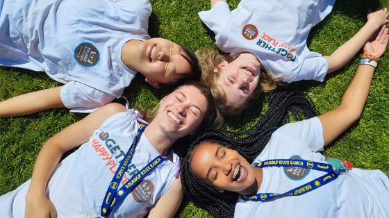smiling camper friends laying on grass