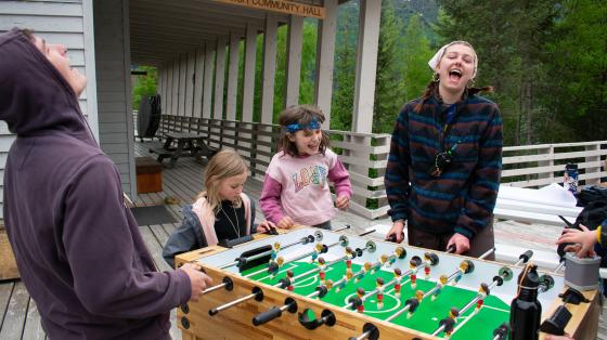 Two counselors playing foosball while two campers watch